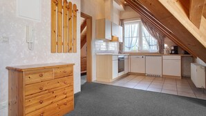 A kitchen with wooden cabinets, a countertop, and a window with curtains. - Obst- und Ferienhof Lehle - Apartment Bodensee with Shared Terrace, Garden and Wi-Fi (Immenstaad am Bodensee)