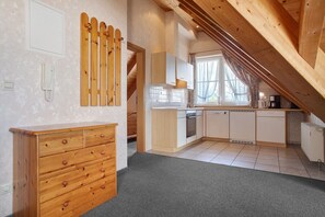 A kitchen with wooden cabinets, a countertop, and a window with curtains.