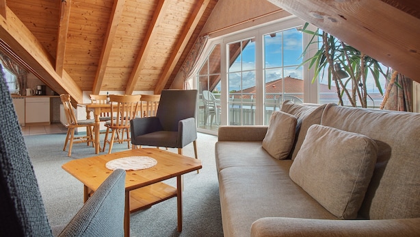 A loft-style room with a wooden ceiling, a sofa, a dining table, and a view through large windows. - Obst- und Ferienhof Lehle - Apartment Bodensee with Shared Terrace, Garden and Wi-Fi (Immenstaad am Bodensee)