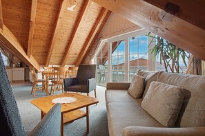 Une pièce de style loft avec un plafond en bois, un canapé, une table à manger et une vue dégagée grâce à de grandes fenêtres.