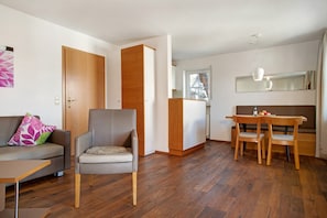 A living room with a sofa, armchair, dining table, and chairs.