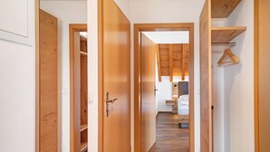 Un pasillo con puertas de madera que dan a un dormitorio con cama y un perchero.
