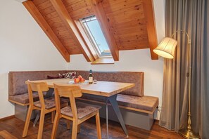 Une pièce de style loft avec un plafond en bois, une lucarne, une table à manger en bois avec des chaises, un banc et un lampadaire.
