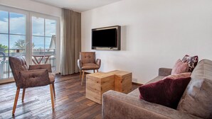 Una sala de estar moderna con sofá, sillones, una mesa de centro de madera y un televisor de pantalla plana montado en la pared.