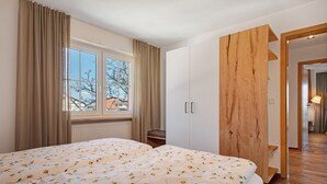 Un dormitorio con una cama grande, un armario de madera y una ventana con cortinas.