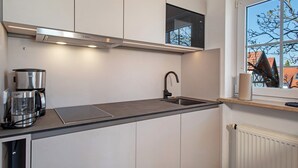 Una cocina moderna con extractor Bosch, cafetera, lavamanos y ventana con vistas a edificios.