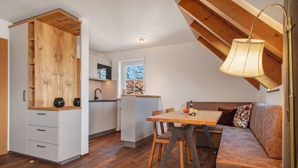 Una habitación estilo loft con zona de comedor, kitchenette y armario de madera.