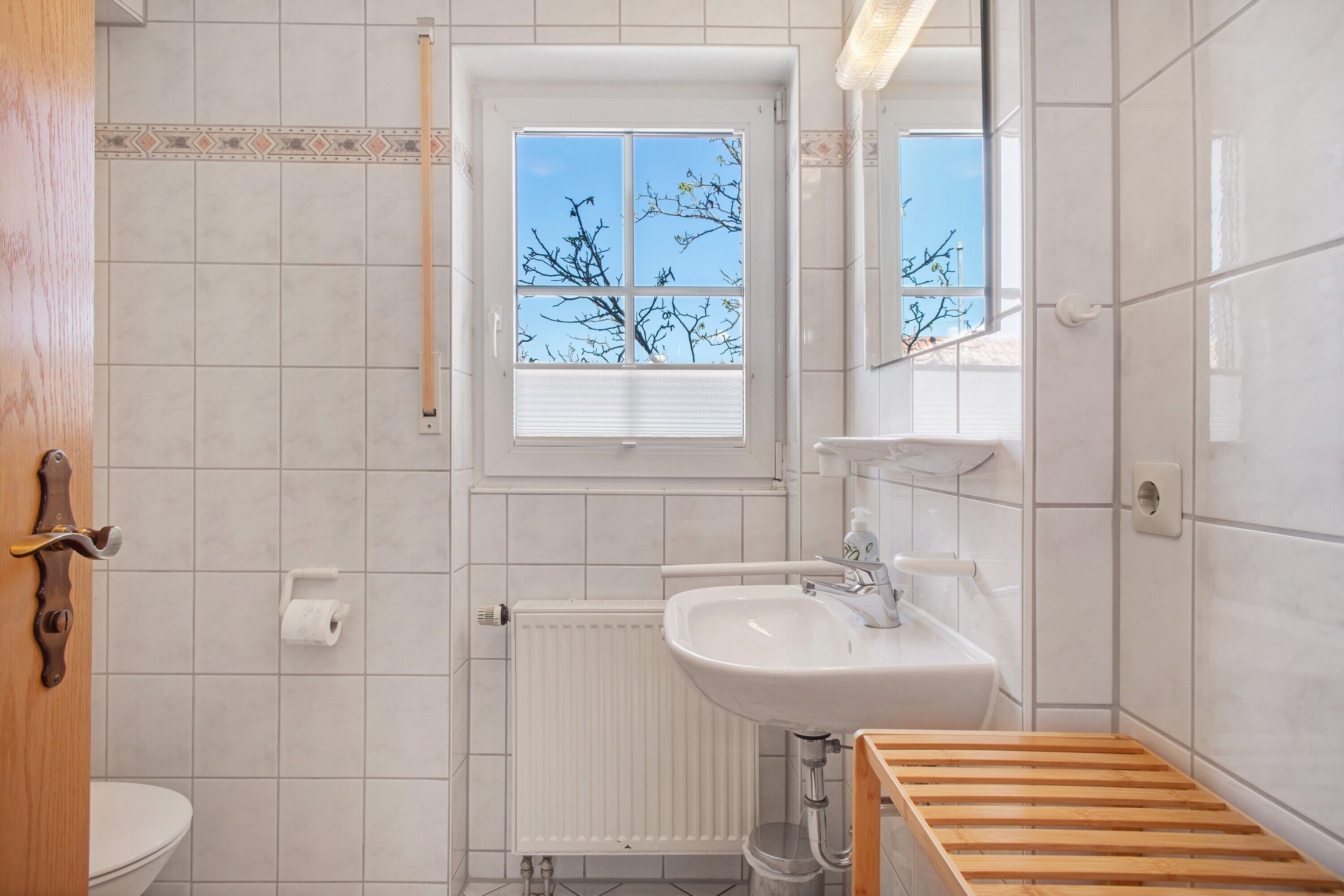 Un bagno con il water, un lavandino, una finestra e una panca di legno.