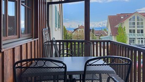 A wooden balcony with metal chairs and a table, overlooking a residential area with houses and a clear sky. - Obst- und Ferienhof Lehle – Apartment Alte Laube with Shared Terrace, Garden & Wi-Fi (Immenstaad am Bodensee)