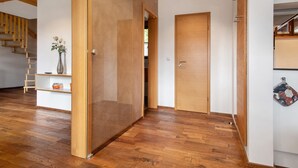 A modern interior with wooden flooring, a sliding door, a staircase, and a wall-mounted rack. - Obst- und Ferienhof Lehle – Apartment Alte Laube with Shared Terrace, Garden & Wi-Fi (Immenstaad am Bodensee)