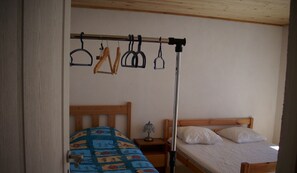 Un dormitorio con una cama de madera, una mesita de noche con lámpara y un tendedero.
