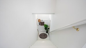 Una escalera blanca que lleva a una puerta con un felpudo estampado.