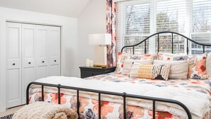 A bedroom with a bed, a nightstand, a lamp, a window with blinds, and a door. - Luxurious Studio in Downtown Douglas (Douglas)