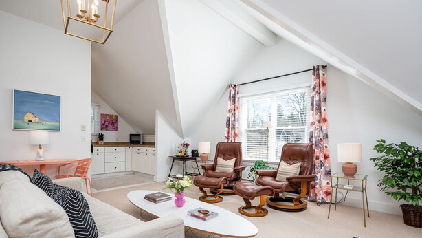 A spacious loft with a high ceiling, a dining area, a living room with leather chairs, a sofa, and a coffee table. - Luxurious Studio in Downtown Douglas (Douglas)