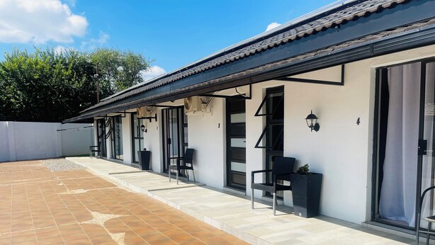 A building with a tiled patio, outdoor seating, and a covered walkway.