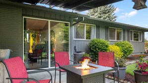 An outdoor patio with a fire feature, red chairs, and a dining area visible through a glass door.
