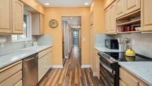 A kitchen with wooden cabinets, a microwave, and a yellow kettle.