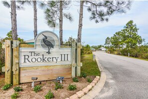 A wooden sign with a bird logo and the text 'The Rookery III' for a property.
