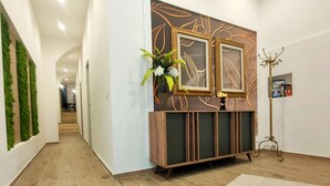A hallway with a wooden floor, a decorative wall panel, and a floor lamp. - San Giovanni Suite Central (Cagliari)