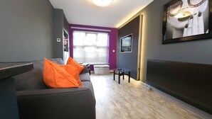 A modern living room with a grey sofa, orange cushions, a small table, and a chair. - Liverpool City, Fairfield Duplex Suite (Liverpool)