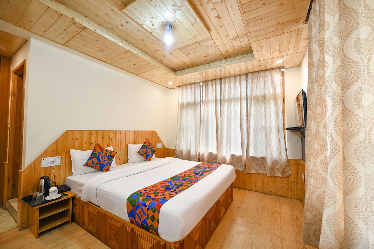 Ein Schlafzimmer mit Holzwänden, einem Bett, einem Nachttisch und Vorhängen.