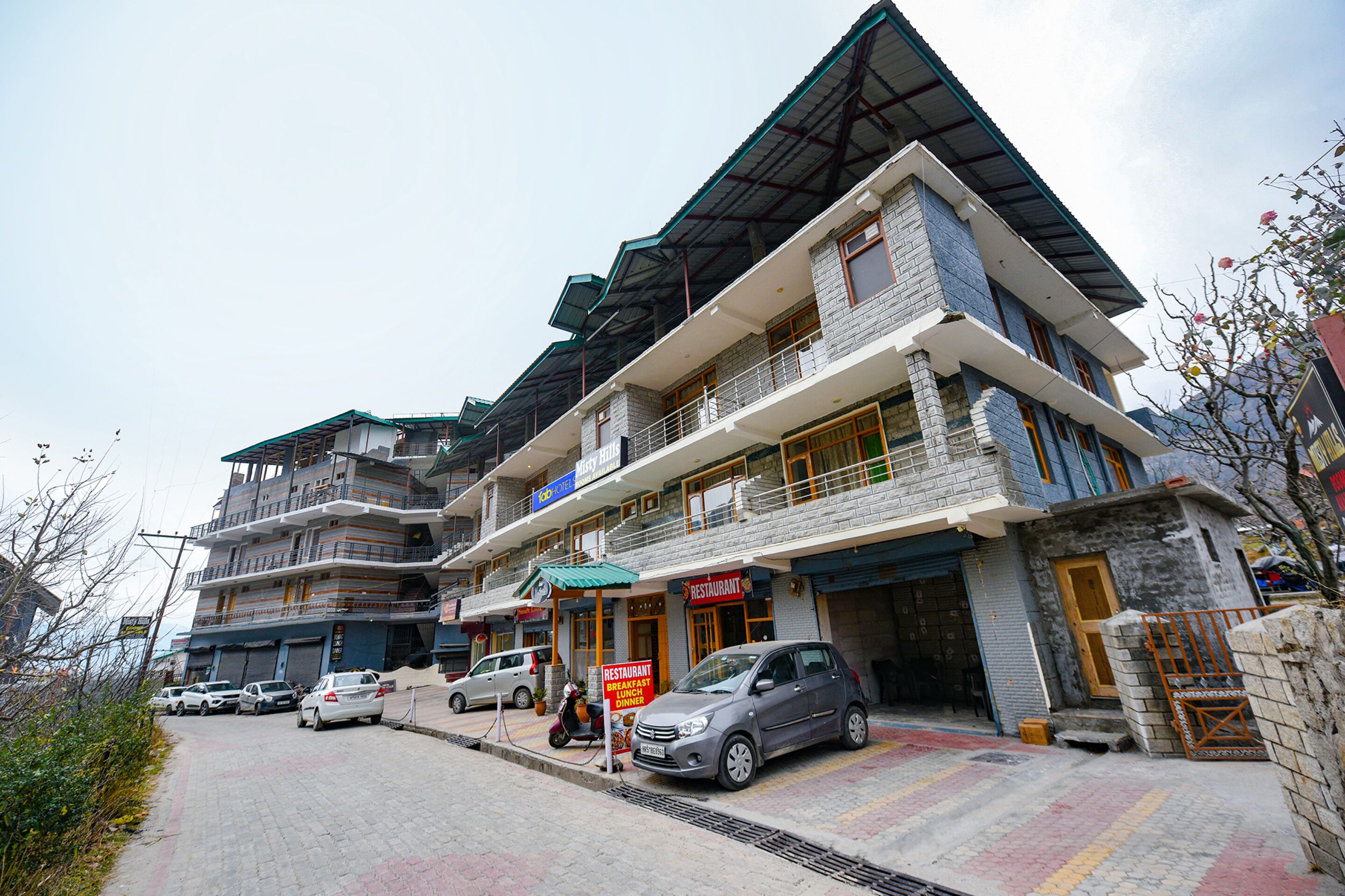 Un immeuble à plusieurs étages, avec un restaurant au rez-de-chaussée, un espace de stationnement et un escalier menant aux étages supérieurs.