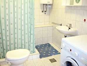 A bathroom with a toilet, a washing machine, a sink, and a shower curtain. - Apartment Serene Step From The Sea, Sleeps 5 (Tkon)