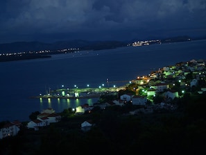A coastal town at night with illuminated buildings and a marina. - Apartment Serene Step From The Sea, Sleeps 5 (Tkon)