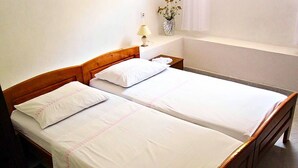 Un lit double avec du linge de lit blanc et une tête de lit en bois.