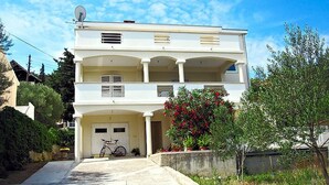 Un immeuble de deux étages avec un balcon au deuxième étage, une antenne parabolique sur le toit et un vélo garé devant.