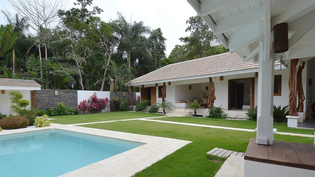 Ein modernes Haus mit Swimmingpool, gepflegtem Rasen und einer Steinsäule.