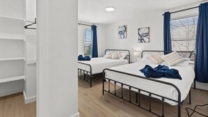 A bedroom with two beds, a wardrobe, and a window with curtains.