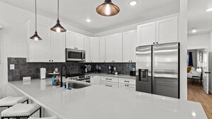 A modern kitchen with white cabinets, stainless steel appliances, and a large island with bar stools.