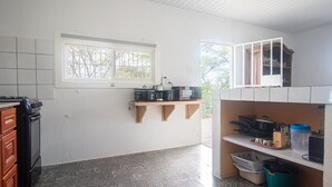 A kitchen with a window, a stove, wooden shelves, and a cabinet. - Aruban Home Close to Beach (Oranjestad)