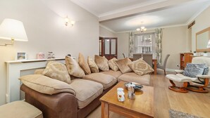 A living room with a brown sofa, a wooden coffee table, and a white armchair.