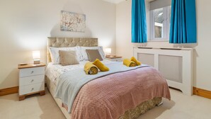 A bedroom with a bed, nightstands, a radiator, and a window with curtains.