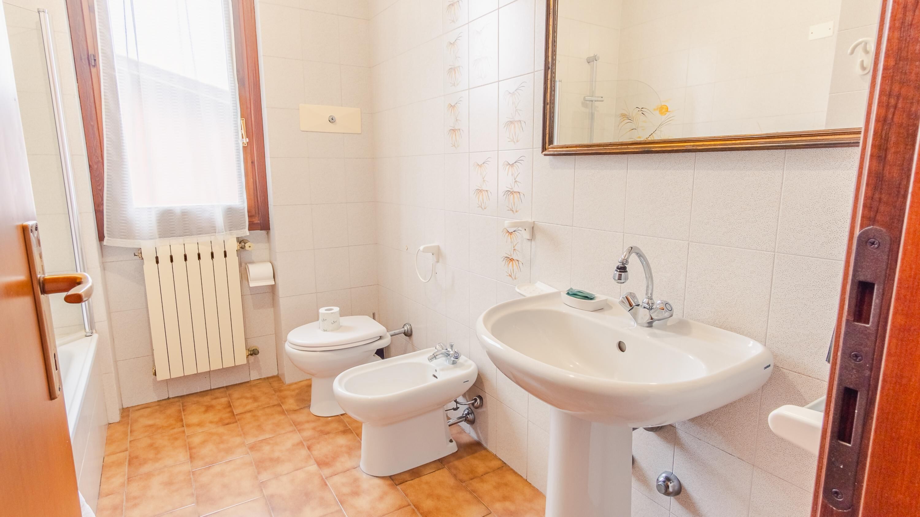 Une salle de bain comprenant des toilettes, un bidet, un lavabo et un miroir.
