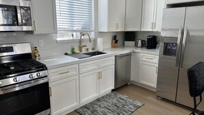 A modern kitchen with white cabinets, stainless steel appliances, a built-in dishwasher, and a coffee maker. - NEW 2BR House IN Glendale Built in 2024 With Garage Private Patio p77 (Glendale)