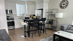A modern kitchen with white cabinets, stainless steel appliances, and a dining area with black chairs and a marble table. - NEW 2BR House IN Glendale Built in 2024 With Garage Private Patio p77 (Glendale)