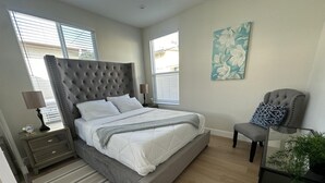 A bedroom with a large bed, a nightstand, a chair, and a painting on the wall. - NEW 2BR House IN Glendale Built in 2024 With Garage Private Patio p77 (Glendale)
