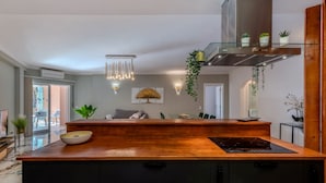 A modern kitchen with a wooden countertop, black cabinets, and a stainless steel range hood.