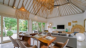 Una sala de estar moderna con comedor, ventanas grandes y televisor.