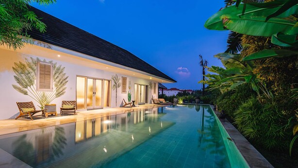 Una casa moderna con piscina, ventanas amplias y plantas tropicales.