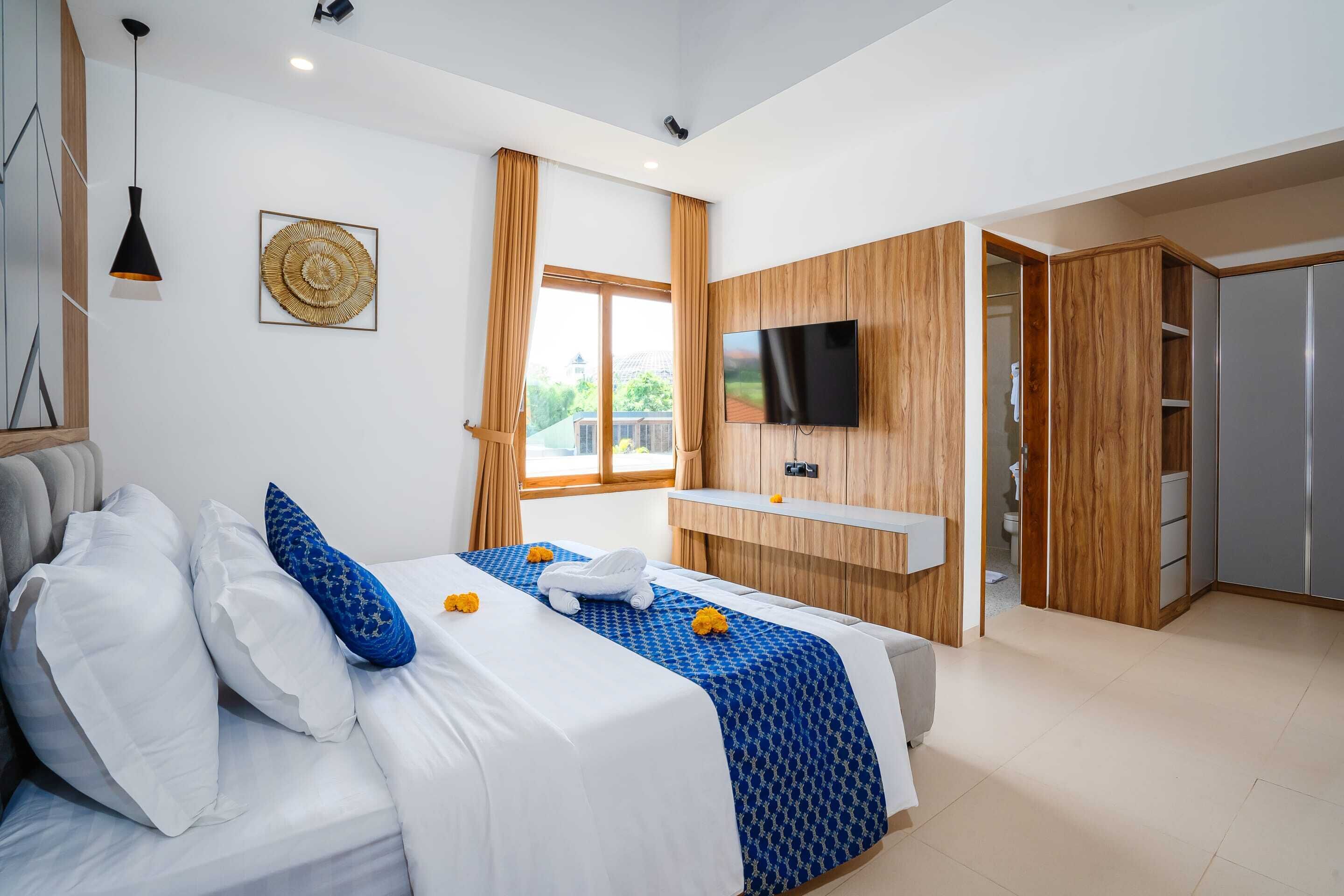 Ett modernt hotellrum med en stor säng, en väggmonterad TV, en garderob i trä och utsikt över omgivningarna.