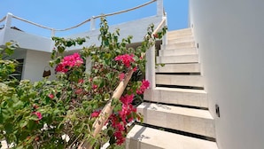 A white building with a staircase and pink flowers in the foreground. - Villa Timatou (Canggu)