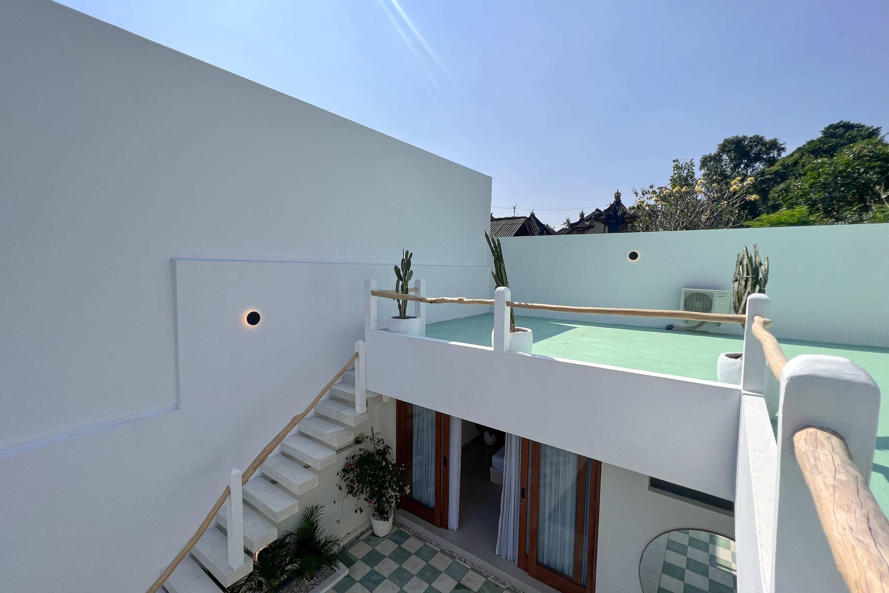 A modern building with a white exterior, a covered outdoor area, and a staircase leading to an upper level.