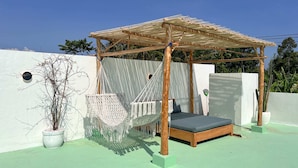 A rooftop with a wooden pergola, a hammock, a bed, and a potted plant. - Villa Soleil (Canggu)
