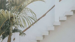 A white staircase leading to a pool area, with a palm tree and a large vase on the ground. - Villa Mood (Canggu)