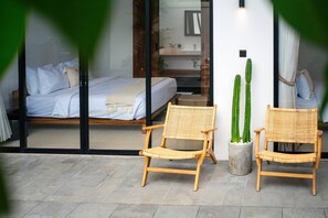 A bedroom with a bed, a bedside table, a mirror, and a potted cactus. - Villa Molly (Canggu)