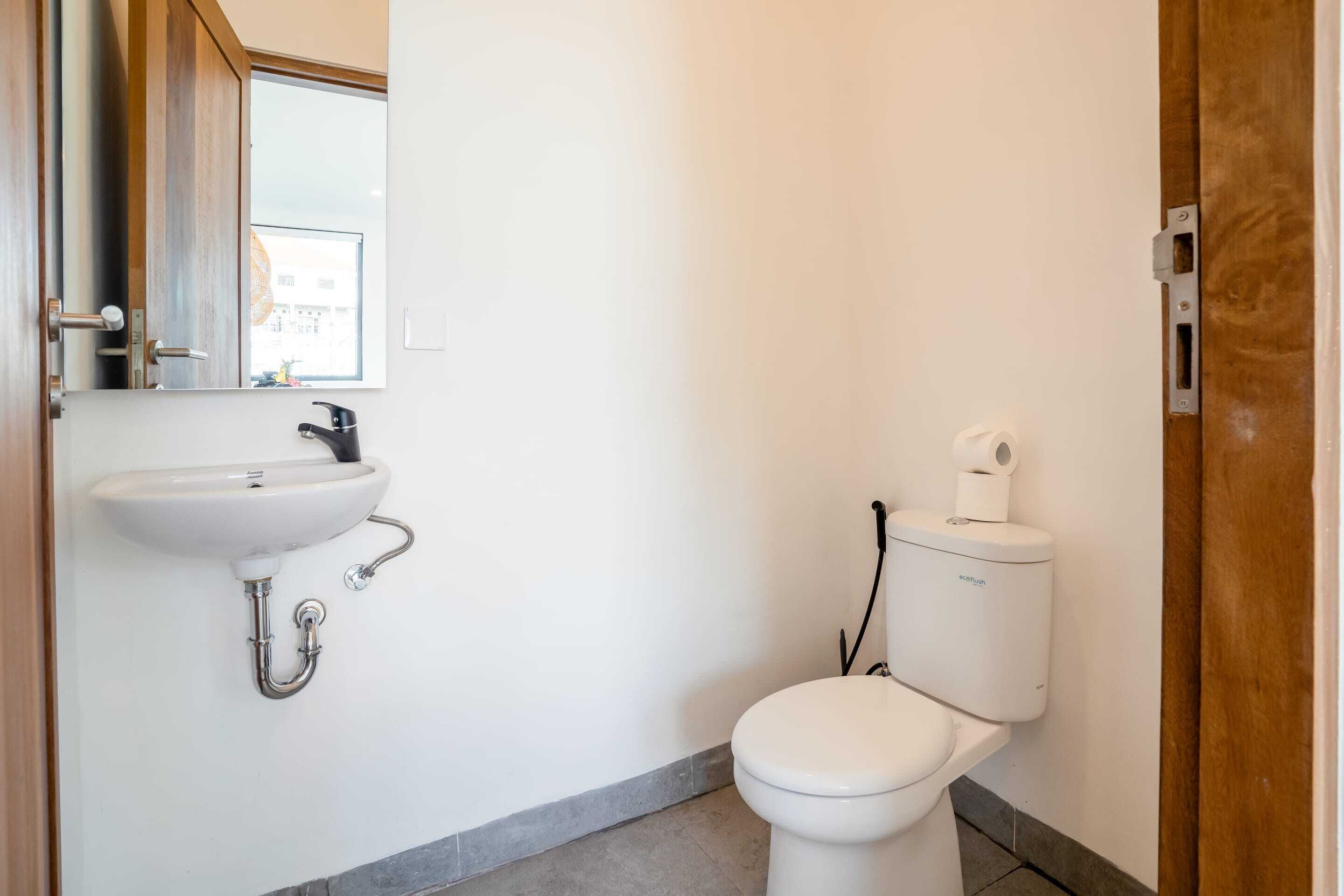 A small, clean bathroom with a white sink, toilet, and mirror.
